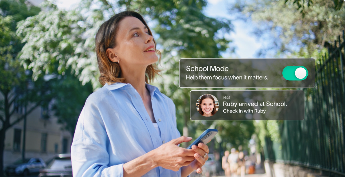 Woman holding a phone with Spacetalk App overlays showing School Mode and a child's school arrival notification.